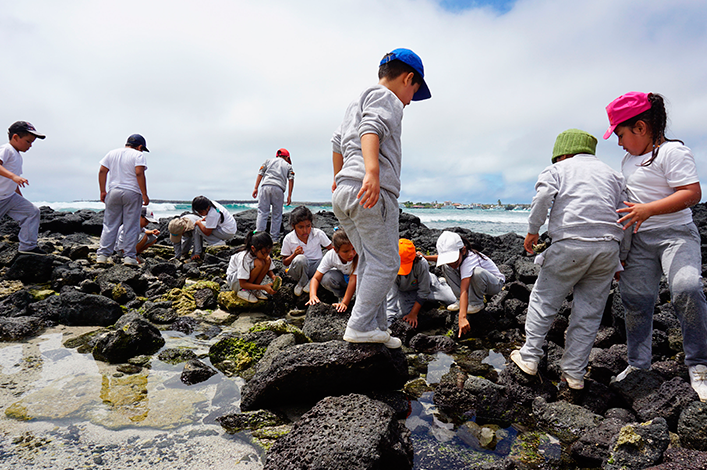 Students of the Oswaldo Guayasamín school of Santa Cruz exploring rocky shores in La Ratonera beach